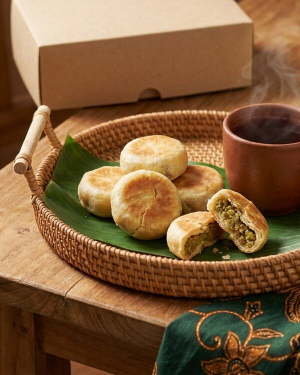 Bakpia kacang hijau di atas nampan rotan dengan secangkir teh hangat